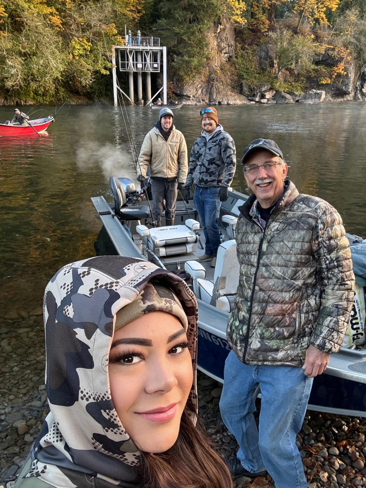 Smiling fishing crew gathered by the jet sled at the river's edge on a crisp autumn morning