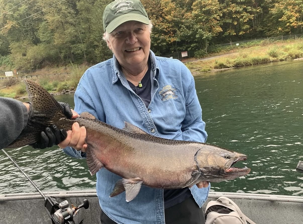Smiling guest holding a large Chinook salmon aboard the boat on a Southwest Washington river